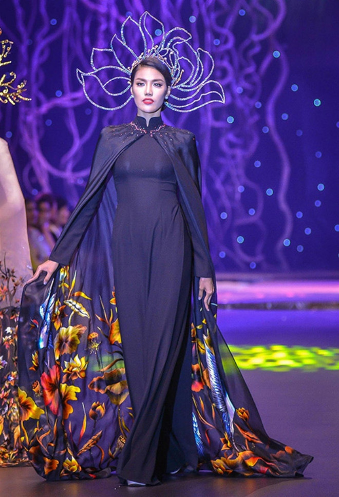 Diện áo dài đen huyền bí, Lan Khuê đẹp cuốn hút, quyền lực. Chiếc mấn bạch kim lấy cảm hứng từ hoa sen, phần tà bay được làm từ vải voan mỏng nhẹ, in hoa văn có màu sắc rực rỡ tạo cảm giác như một biển hoa đong đưa theo từng bước chân khi trình diễn. 